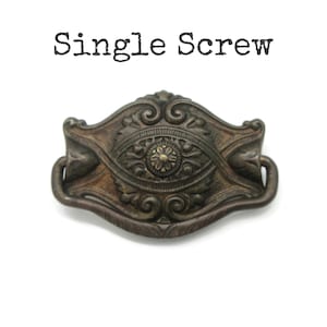 May include: An antique bronze-coloured drawer pull with intricate floral and scrollwork. The pull features a central flower design and two curved handles. The text "Single Screw" is above the pull.