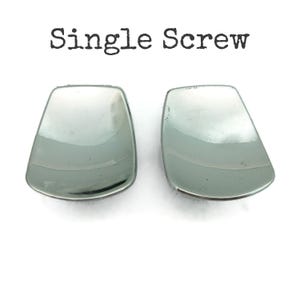 May include: Two silver-colored, curved metal pieces with a reflective surface. The text "Single Screw" is printed above the objects in black.