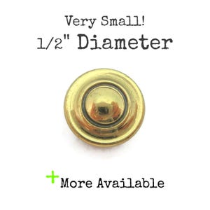 May include: A small, round, metallic gold-toned button with a raised centre and a smooth, reflective surface. The text above the button reads Very Small! 1/2" Diameter, and the text below the button reads + More Available.