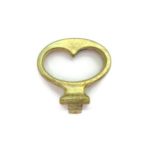 May include: A vintage brass keyhole escutcheon with a heart-shaped handle. The escutcheon has a rectangular base and a slightly aged, golden finish. Suitable for antique furniture restoration or decorative projects.