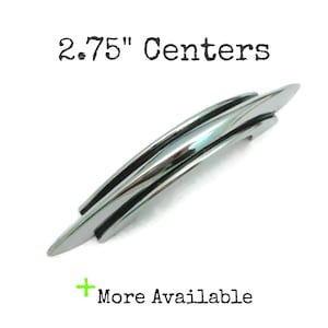 May include: A shiny, chrome-finished cabinet pull with a curved design. The text "2.75" Centers" is above the pull, and "More Available" is below. The pull is approximately 2.75 inches in length.