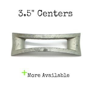 May include: A silver-toned metal drawer pull with a rectangular open centre and curved ends. The text 3.5" Centers is printed above the hardware, and the text + More Available is printed below the hardware in black and green.