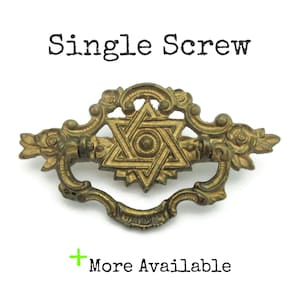 May include: Antique brass drawer pull with a Star of David design. The pull features ornate floral and scrollwork details. The text "Single Screw" is above the pull, and "More Available" is below it.
