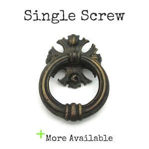 May include: A bronze-coloured drawer pull with a ring handle and decorative backplate. The text "Single Screw" is above the pull, and "More Available" is below it.
