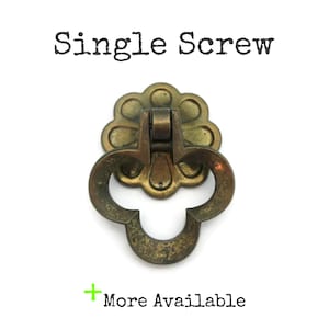 May include: A vintage brass drawer pull with a floral design and a drop handle. The words "Single Screw" are printed above the pull, and "More Available" is printed below it.