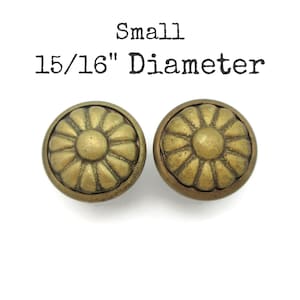 May include: Two small, round, antique brass-colored knobs with a floral design. The knobs are 15/16" in diameter and are set against a white background. The word "Small" is printed above the knobs.