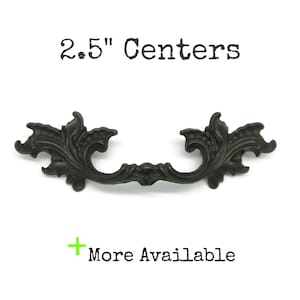 May include: A dark bronze-coloured metal drawer pull with an ornate, scrolling leaf design. The hardware features a 2.5" centre-to-centre measurement for installation. The text "2.5" Centers" and "+ More Available" appear in the image.