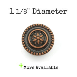 May include: A 1 1/8 inch diameter copper knob with a decorative flower design. The knob has a dark brown finish and a beaded edge.