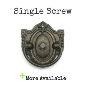 May include: Antique bronze-colored drawer pull with a decorative oval center and a curved handle. The text "Single Screw" is above the pull, and "More Available" is below it.