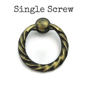 May include: Antique brass-toned drawer pull with a twisted rope design. The pull has a circular ring shape and a small, round knob at the top. The text "Single Screw" is printed above the pull.