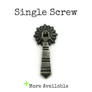 May include: A single antique brass cabinet pull with a starburst design and a pointed bottom. The pull is about 2 inches tall.