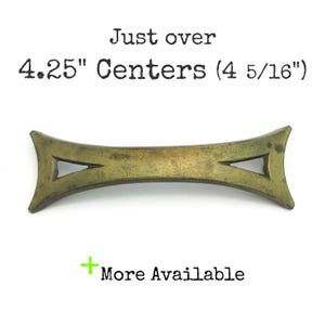 May include: A brass-colored,  decorative drawer pull with a unique,  arrow-shaped design.  The pull measures just over 4.25 inches between the centers.  "Just over 4.25" Centers (4 5/16")" is written above the pull.