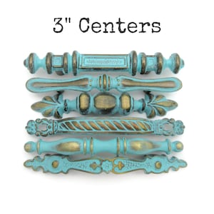 May include: Six decorative cabinet pulls with a distressed turquoise and gold finish. The pulls are 3 inches (7.6 cm) center to center and feature various ornate designs. The text "3" Centers" is displayed at the top.
