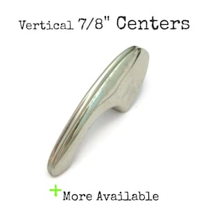 May include: Silver cabinet door pull with a curved design. The pull is 7/8" in diameter. Vertical 7/8" Centers.