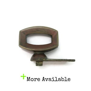 May include: A vintage brass cabinet pull featuring a hexagonal frame with a central horizontal opening and a flat, rectangular mounting arm extending to the right. The metal surface shows signs of age and patina. Text reads: + More Available.