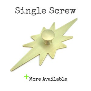 May include: A gold-toned starburst-shaped cabinet knob with a single screw. The knob is made of metal and has a smooth, polished finish.