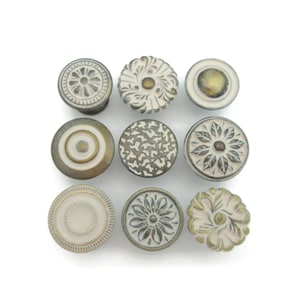 May include: Set of eight decorative cabinet knobs with a white and gold finish. Each knob features a different floral design.