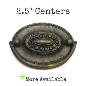 May include: An oval-shaped bronze-toned metal drawer pull with a rope-style border and a central decorative medallion featuring small raised circles. The hardware includes a drop handle and is labeled with the text 2.5" Centers and More Available.