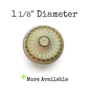 May include: A round, antique-style knob with a diameter of 1 1/8 inches. The knob has a light green and gold color scheme with a textured, ridged design. The text "More Available" is displayed in green.