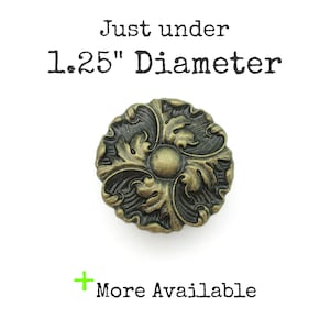 May include: An antique-style bronze knob with an ornate floral design. The knob is just under 3.2 cm in diameter. The text "Just under 1.25" Diameter" and "More Available" are also visible.