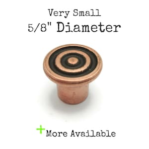May include: A small, copper-colored cabinet knob with a concentric circle design. The knob has a 5/8" diameter and the text "Very Small" and "More Available" are visible.