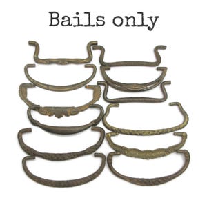 May include: A collection of ten assorted metal drawer bails with various antique brass and bronze finishes, featuring decorative embossed patterns and curved shapes. The text "Bails only" is printed in black at the top of the image.