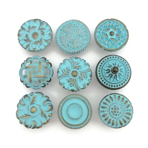 May include: Nine turquoise blue and gold decorative cabinet knobs with various ornate designs.