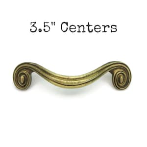 May include: An antique brass-toned metal drawer pull with a curved, wave-like shape and spiral ends. The handle features a textured, weathered finish. Above the handle, the text 3.5" Centers is printed in a dark, typewriter-style font.