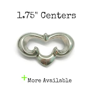 May include: A silver-toned metal drawer pull with a symmetrical, curved design featuring two open loops and a central point. The text 1.75" Centers is printed above the object, and the text + More Available is printed below the object.