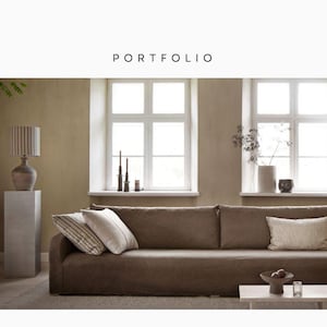 Puede incluir: Portafolio de diseño de interiores con un sofá marrón, cojines, una mesa auxiliar y una lámpara. La habitación tiene grandes ventanas y paredes de tonos neutros. La palabra "PORTFOLIO" está arriba.