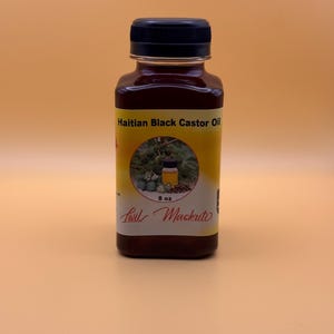 May include: A brown glass bottle with a black cap, labeled "Haitian Black Castor Oil." The label includes an image and the text "8 oz" and "Lwil Maskriti."