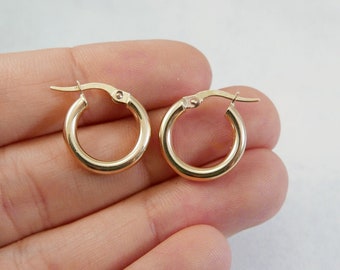 May include: A pair of gold hoop earrings. The earrings are simple and classic, with a smooth finish.
