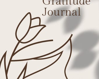 May include: A beige journal with the words "90 Day Gratitude Journal" in dark brown. A brown floral line drawing is on the left side. The journal has a shadow effect and a small logo in the bottom right corner.