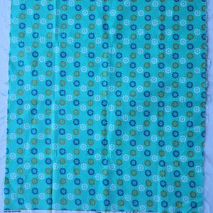 Puede incluir: Un trozo rectangular de tela turquesa con un patrón floral repetido en blanco, azul y dorado. La tela tiene texto en la parte inferior que dice "LEAT AND THE NET WILL APPEAR" y "COTTON + STEEL".