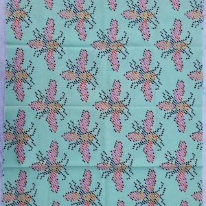 Puede incluir: Un trozo de tela con un patrón repetido de diseños florales estilizados. Las flores están compuestas por pequeñas formas coloridas en rosa, amarillo, naranja y negro, sobre un fondo verde claro. La tela está etiquetada como "Cotton + Steel Spring 2014".