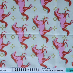 Może przedstawiać: Tkanina z powtarzającym się wzorem różowych koni w pozycji wspinającej się, obrysowanych na turkusowo, na jasnokremowym tle. Konie mają czerwone grzywy i ogony, z małymi złotymi wzorami w kształcie krzyża. Tekst na dole tkaniny.