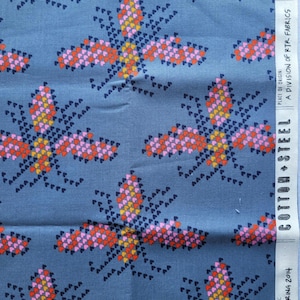 Puede incluir: Tela azul con un patrón repetido de diseños florales estilizados en rosa, naranja y amarillo. La tela tiene una etiqueta Cotton + Steel con el texto "Spring 2014" y "Made in Japan".
