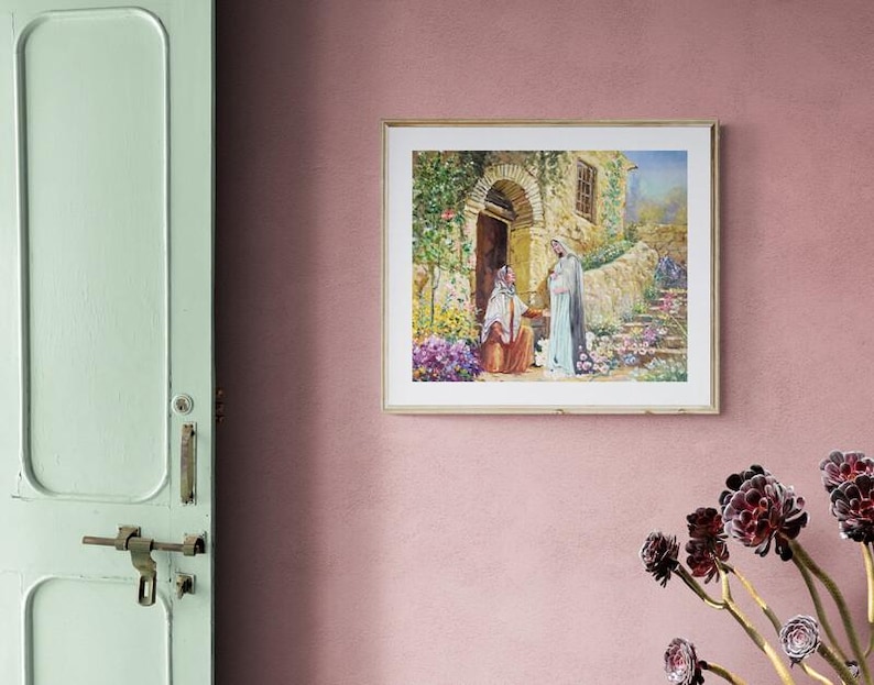 May include: A framed print depicting a religious scene with figures in flowing robes, set in a stone building with an arched doorway. The artwork features vibrant colors and is surrounded by a gold frame, mounted on a pink wall.