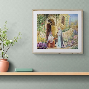 May include: A framed print depicting a religious scene with two figures in a garden setting. The artwork features a stone building with an arched doorway, lush greenery, and colorful flowers. The print is displayed on a light-colored wooden shelf.