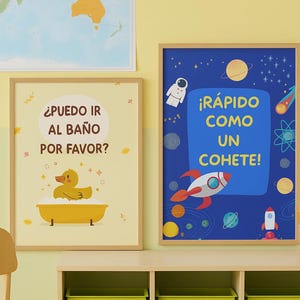 May include: Two framed prints with a children's theme. One features a yellow rubber duck in a bathtub with the text "¿PUEDO IR AL BAÑO POR FAVOR?" The other has a rocket ship and the text "¡RÁPIDO COMO UN COHETE!"
