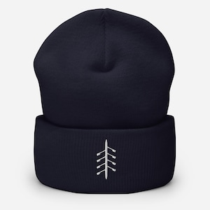 May include: A navy blue cuffed beanie featuring a small, white embroidered graphic of a rowing shell with four oars extending from the center. The knit hat has a structured crown and a thick, folded brim, showcasing a clean, simple design.