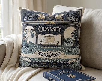 May include: Decorative throw pillow with a navy blue and cream design featuring a ship, waves, and the text "The Odyssey by Homer." A matching book is also visible. The pillow is on a beige sofa.