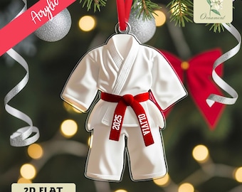 May include: A white karate uniform ornament with a red belt. The belt has the name "Olivia" and the year "2025" printed on it. The ornament is hanging from a red ribbon. The word "Acrylic" is printed on a red banner. The words "2D Flat Ornament" are printed on a white rectangle.