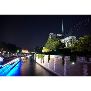Bateau Bleu - 夜にパリのノートルダム大聖堂を通過する観光船のマット加工された写真。