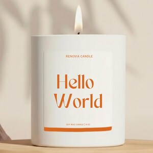 May include: A lit white soy wax candle with the text "Hello World" in orange. The candle is in a white cylindrical container with the text "RENOVIA CANDLE" above the main text and "SOY WAX CANDLE | 9 OZ" below.
