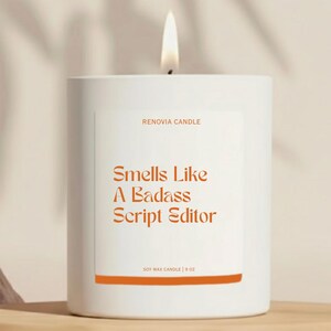 May include: A white soy wax candle with the text "Smells Like A Badass Script Editor" in orange. The candle is 9 oz and has a lit wick. The brand name "RENOVIA CANDLE" is printed above the text.