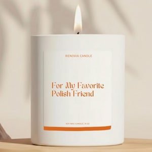 May include: A lit white soy wax candle with the text "For My Favorite Polish Friend" in orange. The candle is 9 oz and has the brand name "Renovia Candle" printed on the label. The candle is on a wooden shelf.