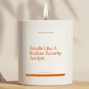 May include: A white candle with a lit flame. The label reads "RENOVIA CANDLE" and "Smells Like A Badass Security Analyst." The candle is soy wax and weighs 9 oz.