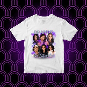 Pode incluir: Camiseta branca com um gráfico de várias mulheres, o texto "Brandy" e "The Boy Is Mine" em roxo e azul. A camiseta tem gola redonda e mangas curtas.