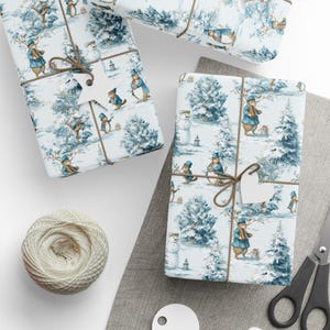 May include: Gift-wrapped presents with a winter scene featuring woodland creatures in blue coats and hats. The gifts are tied with twine and adorned with white star-shaped tags. A ball of twine and scissors are also visible.